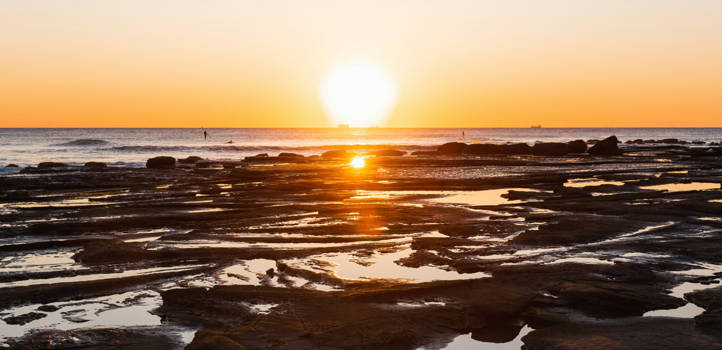 Bildet viser en solnedgang over en strand.